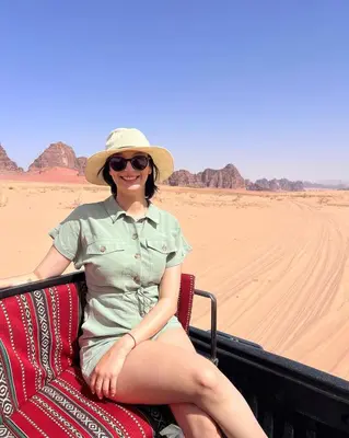 a woman sitting in the back of a truck in the desert at Wadi Rum Maracanã camp in Wadi Rum