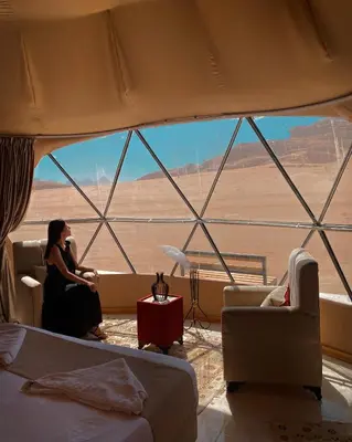 a woman sitting in a room with a view of a desert at Wadi Rum Maracanã camp in Wadi Rum