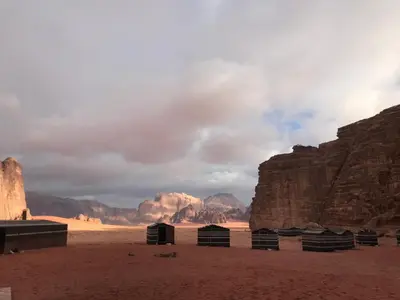 a desert scene with mountains and buildings in the foreground at Wadirum momoo in Wadi Rum