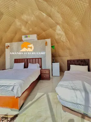a bedroom with two beds and a sign on the wall at Amanda Luxury Camp in Wadi Rum