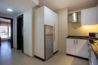a kitchen with white cabinets and a refrigerator at Triple A Hotel Suites in Amman