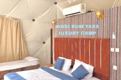 a bedroom with two beds and a tv on the wall at WADI RUM TARA lUXURY CAMP in Wadi Rum