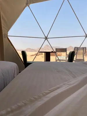 a tent with a table and chairs in the desert at WADI RUM TARA lUXURY CAMP in Wadi Rum