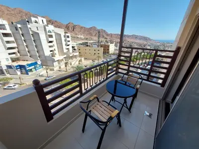 a balcony with two chairs and a view of the city at Jordan Seasons Hotel in Aqaba