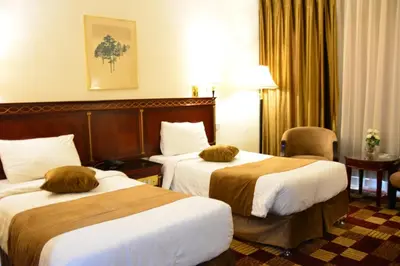 a hotel room with two beds and a table at Rakeen Hotel in Amman