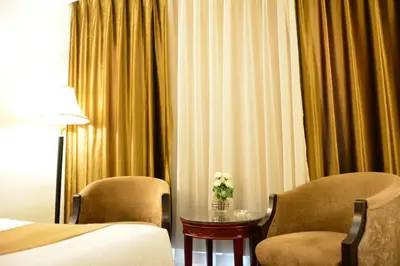 a hotel room with two chairs and a table with flowers at Rakeen Hotel in Amman