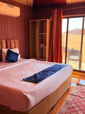 a bedroom with a large bed with a large window at NAEL BEDOUIN lUXURY CAMP in Wadi Rum