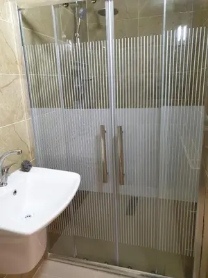a bathroom with a glass shower with a sink at atoom studio in Jerash