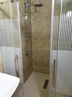 a shower with a glass door in a bathroom at atoom studio in Jerash