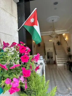 a flag on the side of a house with flowers at City Citadel Hotel,Amman in Amman