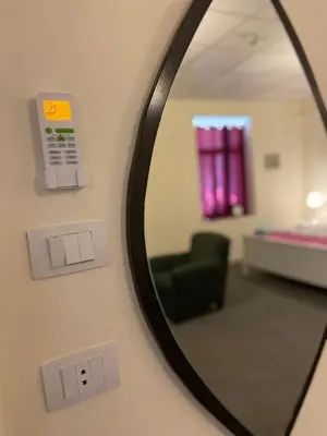 a mirror on a wall with a chair and a room at City Citadel Hotel,Amman in Amman