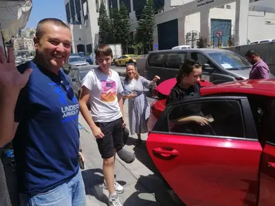 a group of people standing next to a red car at City Citadel Hotel,Amman in Amman