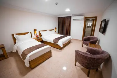 a hotel room with two beds and a chair at Joar Beach Hotel in Aqaba