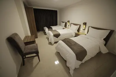 a hotel room with two beds and a chair at Joar Beach Hotel in Aqaba