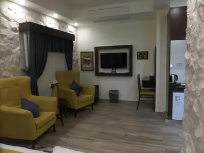 a waiting room with yellow chairs and a flat screen tv at Mount Nebo Hotel & Restaurant Madaba City Center in Madaba