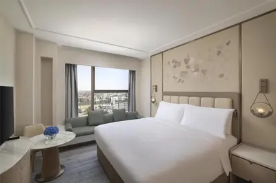 a bedroom with a large white bed and a couch at Signia by Hilton in Amman