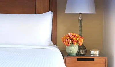 a bed with a lamp and a vase with flowers on a night stand at InterContinental Amman Jordan by IHG in Amman