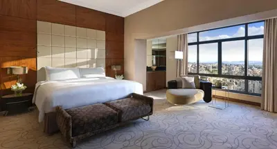 a bedroom with a bed and a chair and a large window at InterContinental Amman Jordan by IHG in Amman