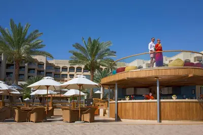 a group of people standing on a building with tables and umbrellas at InterContinental Aqaba by IHG in Aqaba