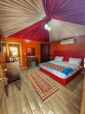 a bedroom with a large bed and a red ceiling at Rum Oasis Luxury Camp in Wadi Rum
