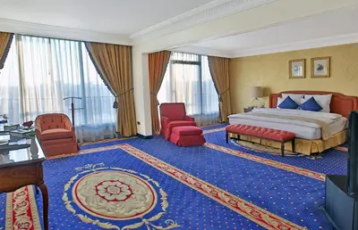 a hotel room with a bed and a desk and chairs at Regency Palace Amman in Amman