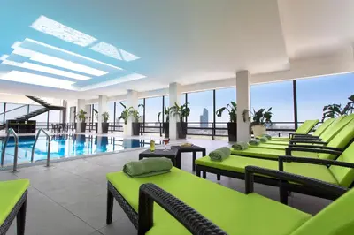 a pool room with green chairs and a swimming pool at Regency Palace Amman in Amman