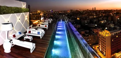 a rooftop bar with a view of a city at night at Regency Palace Amman in Amman