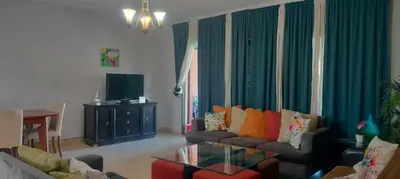 a living room with a couch and a tv at Gorgeous Pool View Apartment - Tala Bay Resort, Aqaba in Aqaba