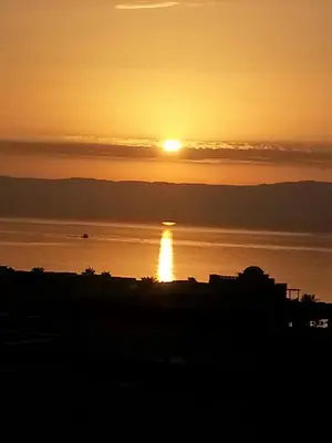 a sunset over a body of water with the sun setting at Gorgeous Pool View Apartment - Tala Bay Resort, Aqaba in Aqaba