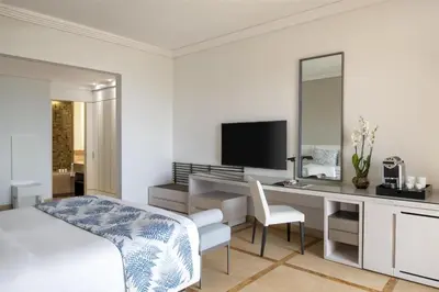 a bedroom with a bed and a desk with a mirror at Kempinski Hotel Ishtar Dead Sea in Sowayma