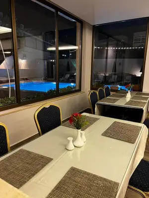 a dining room with tables and chairs and a pool at Salome Hotel in Madaba