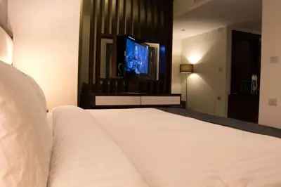 a bedroom with a white bed and a tv at Seas Hotel Amman in Amman