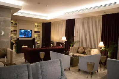 a living room with chairs and a television and a couch at Seas Hotel Amman in Amman