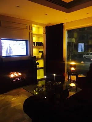 a living room with a fireplace and a television at Seas Hotel Amman in Amman