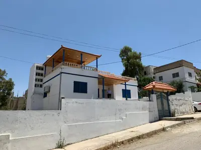 a small white house with a wooden roof at Gedara Guesthouse: enjoy unforgettable scenes in Um Qeis