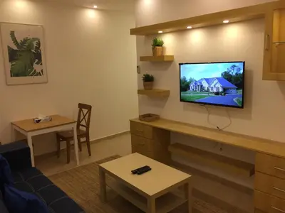a living room with a tv on a wall at Superior Executive Apartment in Umm Uthainah
