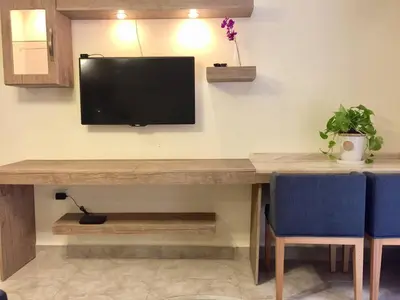 a desk with a television on a wall with two blue chairs at The Royal Luxury King Terrace 1 in Amman