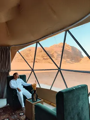 a man sitting in a chair in front of a window at Wadi Rum Relaxation Camp in Wadi Rum