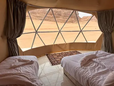 a bedroom with a large window and a bed in a room at Wadi Rum Relaxation Camp in Wadi Rum
