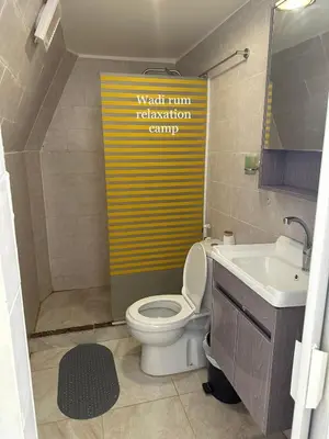 a bathroom with a toilet and a yellow sign at Wadi Rum Relaxation Camp in Wadi Rum