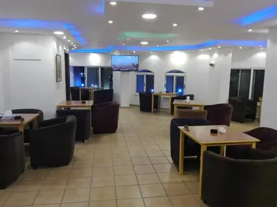 a waiting room with tables and chairs and a screen at Razan Hotel in Amman