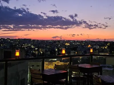 a view of a city at sunset from a balcony at Saint John Hotel in Madaba