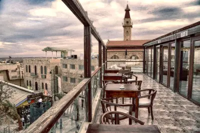 a balcony with tables and chairs and a clock tower at Saint John Hotel in Madaba