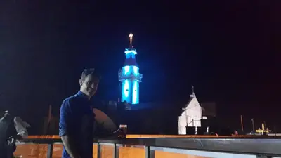 a man standing in front of a clock tower at night at Saint John Hotel in Madaba
