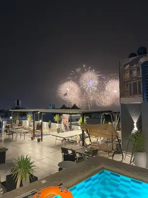 a rooftop patio with a swimming pool with fireworks at Mass Paradise Hotel in Aqaba