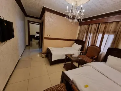 a hotel room with two beds and a chandelier at Nahas Plaza in Irbid
