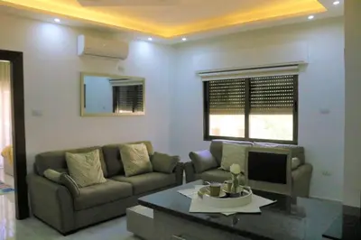 a living room with a couch and a table at Amazing one Bedroom Apartment in Amman Elwebdah 7 in Amman