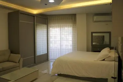 a bedroom with a bed and a chair and a window at Amazing one Bedroom Apartment in Amman Elwebdah 7 in Amman