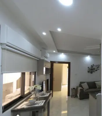 a kitchen and living room with a couch and a table at Amazing one Bedroom Apartment in Amman Elwebdah 8 in Amman