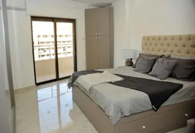a bedroom with a large bed with a large window at Amazing one Bedroom Apartment in Amman Elwebdah 2 in Amman